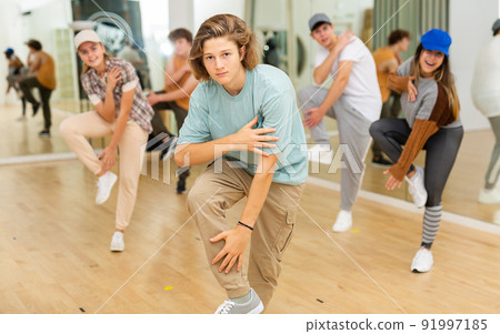 Teenage boy practicing hip-hop movements with group in studio Teenage boy practicing hip-hop movements with group in studio 91997185