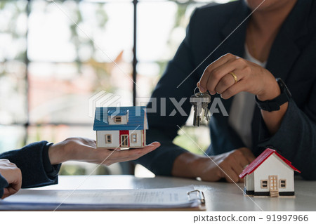 Close up Businessman or Real Estate agent giving house key after signing agreement for buying house. Bank manager and real estate concept. Close up Businessman or Real Estate agent giving house key after signing agreement for buying house. Bank manager and real estate concept. 91997966