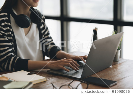 Woman focusing on webinars online class. Student wearing headphone to listening online class. Woman focusing on webinars online class. Student wearing headphone to listening online class. 91998056