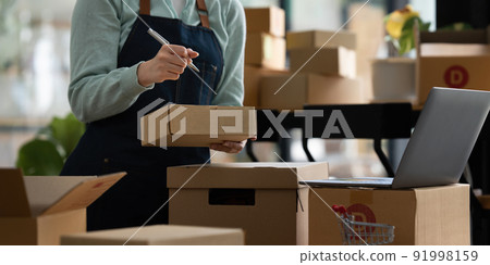 Image of Young asian woman startup freelance with product and showing to customer by computer laptop. Online marketing packing box delivery concept. Image of Young asian woman startup freelance with product and showing to customer by computer laptop. Online marketing packing box delivery concept. 91998159