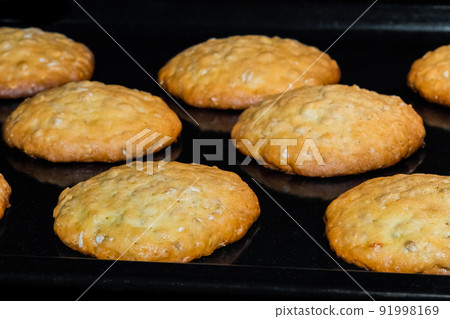 Many baked homemade crunchy oatmeal cookies on metal sheet in oven 91998169