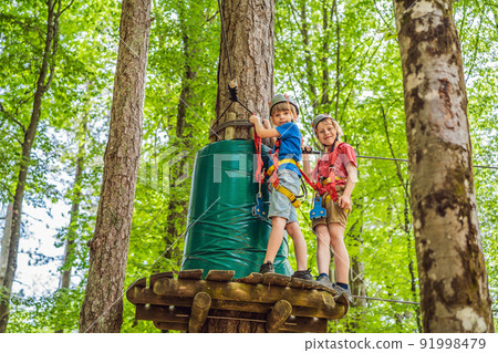 Two boys in a helmet, healthy teenager school boy enjoying activity in a climbing adventure park on a summer day 91998479