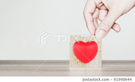 Hand put a red heart shape icon on wooden cubes block on wood table. Concept of setting goals to have a girlfriend. 91998644