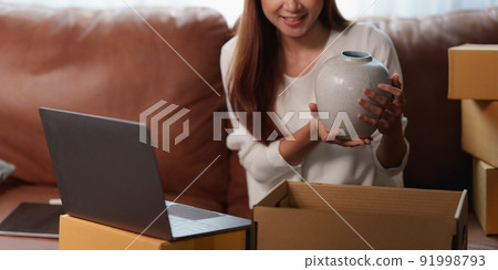 Image of Young asian woman startup freelance with parcel box and talking with customer by computer laptop. Online marketing packing box delivery concept. Image of Young asian woman startup freelance with parcel box and talking with customer by computer laptop. Online marketing packing box delivery concept. 91998793