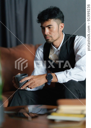 Portrait of Asian Businessman with cup of coffee and sitting at cozy sofa. Portrait of Asian Businessman with cup of coffee and sitting at cozy sofa. 91999236