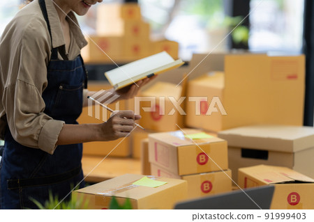 Asian small business owner working at home office. Business retail market and online sell marketing delivery, SME e-commerce concept. Asian small business owner working at home office. Business retail market and online sell marketing delivery, SME e-commerce concept. 91999403