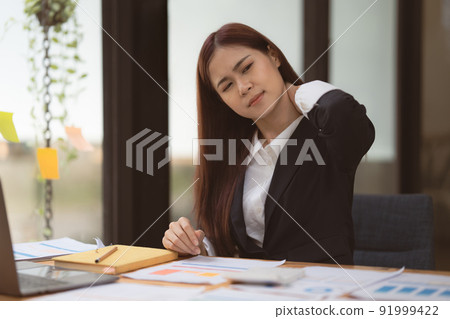 Image of Asian Business Woman relieve pain her neck suffering from sedentary work. office syndrome concept. Image of Asian Business Woman relieve pain her neck suffering from sedentary work. office syndrome concept. 91999422