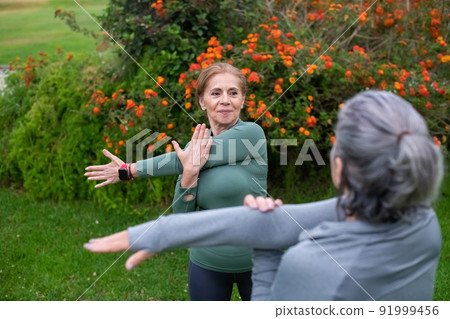 Active senior friends exercising in park Active senior friends exercising in park 91999456