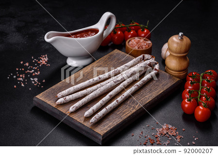 Delicious dry sausage with walnuts on a concrete table. Dry cured fuet sausage on a dark background 92000207