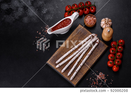 Delicious dry sausage with walnuts on a concrete table. Dry cured fuet sausage on a dark background 92000208