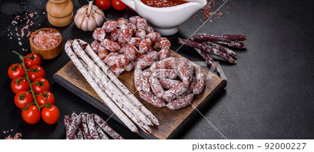 Delicious dry sausage with walnuts on a concrete table. Dry cured fuet sausage on a dark background Delicious dry sausage with walnuts on a concrete table. Dry cured fuet sausage on a dark background 92000227