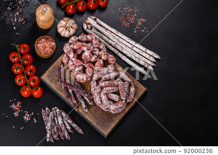 Delicious dry sausage with walnuts on a concrete table. Dry cured fuet sausage on a dark background Delicious dry sausage with walnuts on a concrete table. Dry cured fuet sausage on a dark background 92000236
