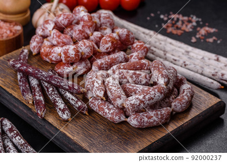 Delicious dry sausage with walnuts on a concrete table. Dry cured fuet sausage on a dark background Delicious dry sausage with walnuts on a concrete table. Dry cured fuet sausage on a dark background 92000237