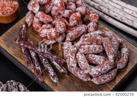 Delicious dry sausage with walnuts on a concrete table. Dry cured fuet sausage on a dark background Delicious dry sausage with walnuts on a concrete table. Dry cured fuet sausage on a dark background 92000239