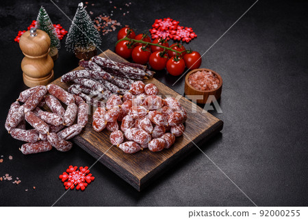 Delicious dry sausage with walnuts on a christmas table. Dry cured fuet sausage on a dark background 92000255