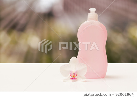 Bottle of dishwashing liquid and orchid flower on blurred background. 92001964