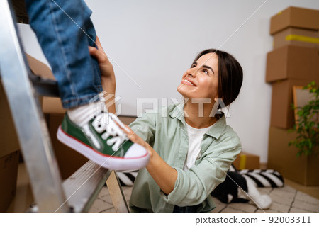 Beautiful smiling woman and little boy with cardboard boxes moving to new home Beautiful smiling woman and little boy with cardboard boxes moving to new home 92003311