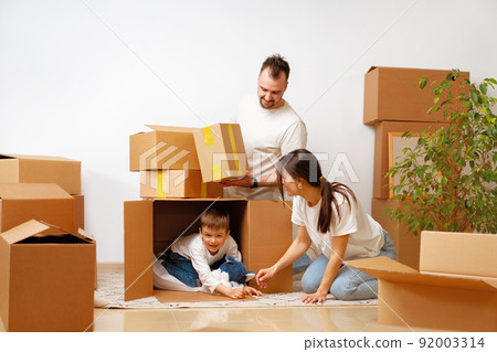 Young parents and son having fun during moving day to new house 92003314