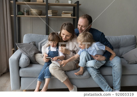 Parents and kids sit on sofa with a book 92003319
