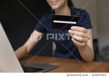 Young woman holding black credit card close up Young woman holding black credit card close up 92003402