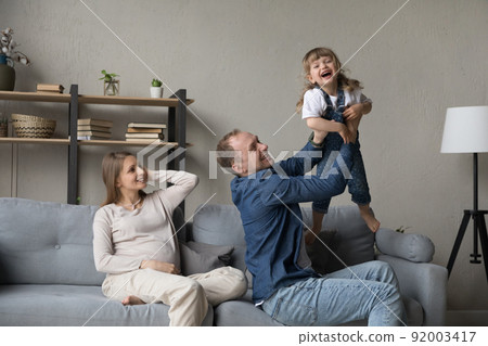 Pregnant woman looks how husband play with cute little daughter 92003417