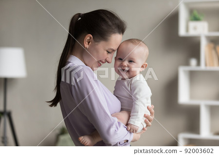 Laughing mother and cheerful adorable newborn child indoor 92003602