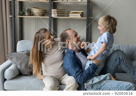 Pregnant woman her husband and son playing seated on sofa Pregnant woman her husband and son playing seated on sofa 92003616
