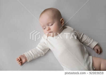 Above closeup shot calm newborn sleeping on bed Above closeup shot calm newborn sleeping on bed 92003659