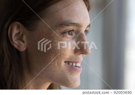 Profile view face of young freckled female staring into distance Profile view face of young freckled female staring into distance 92003690