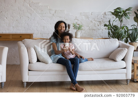 African woman and daughter spend leisure using modern smartphone African woman and daughter spend leisure using modern smartphone 92003779