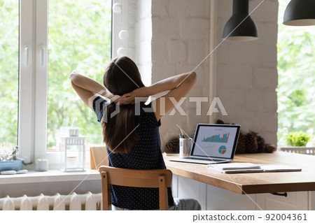 Tired freelancer woman relaxing at workplace, stretching body 92004361