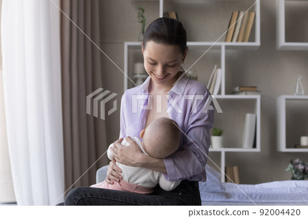 Young beautiful mother breastfeeding her newborn baby at home Young beautiful mother breastfeeding her newborn baby at home 92004420
