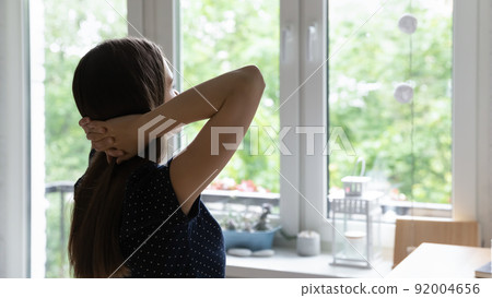 Dreamy young woman sitting at home table, looking at window Dreamy young woman sitting at home table, looking at window 92004656