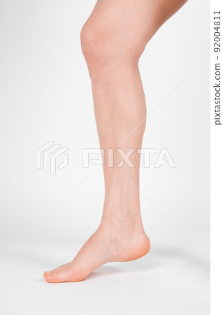 Barefoot and legs isolated on white background. Closeup shot of healthy beautiful female feet. Health and beauty concept. Side view of human foot ream with neutral manicure or pedicure. Sole of foot. 92004811