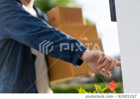 Asian postman with a hygiene protective face mask picking up a parcel package or parcel box from the truck for deliver to customer's door. New Normal concept during covid-19 or coronavirus pandemic Asian postman with a hygiene protective face mask picking up a parcel package or parcel box from the truck for deliver to customer's door. New Normal concept during covid-19 or coronavirus pandemic 92005287
