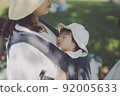 A baby sleeping comfortably in a hug in the shade of a tree 92005633