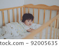 A baby staring at you quietly from the crib 92005635