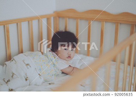 A baby staring at you quietly from the crib 92005635