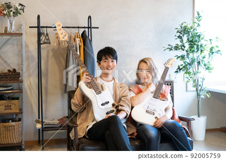 年輕男女在客廳裡彈吉他和貝斯 年輕男女在客廳裡彈吉他和貝斯 92005759