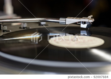 Focus on The Headshell Cartridge and Stylus of Classic Vintage Vinyl Record Player or Turntable Playing on Vinyl Record Music 92007884