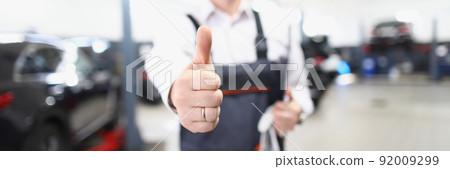 Car maintenance service worker show thumbs up and happily smile Car maintenance service worker show thumbs up and happily smile 92009299