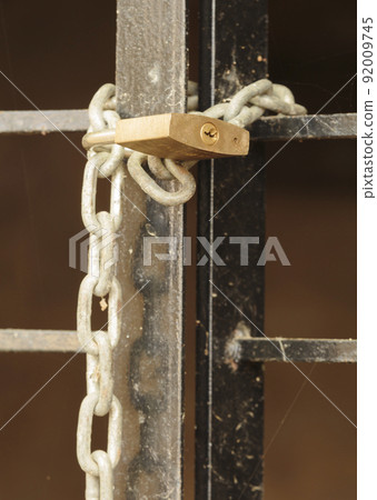Close up image of a padlock closing a barred door Close up image of a padlock closing a barred door 92009745