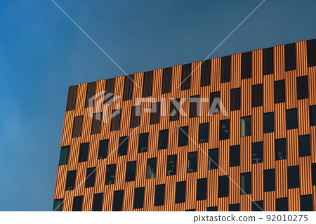 Modern office building exterior with glass facade on clear sky background. Transparent glass wall of office building with orange decoration. Element of facade of modern European building Commercial 92010275