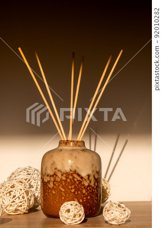 Cozy home decorations aroma reed diffuser in the living room. Home comfort concept. Bottle container with wood stick diffusers Essential oils to scent your home Minimalist air freshener concept. 92010282