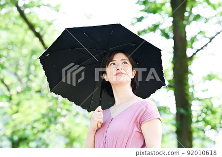 一個女人在公園裡打著陽傘散步 92010618