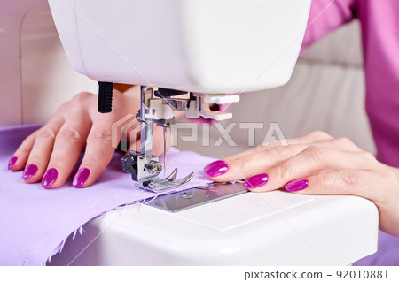 Woman sewing a dress on a sewing machine. Close-up, selective focus Woman sewing a dress on a sewing machine. Close-up, selective focus 92010881