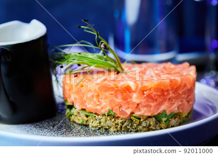 Salmon tartare with avocado on a white plate in a restaurant. Close-up, selective focus 92011000