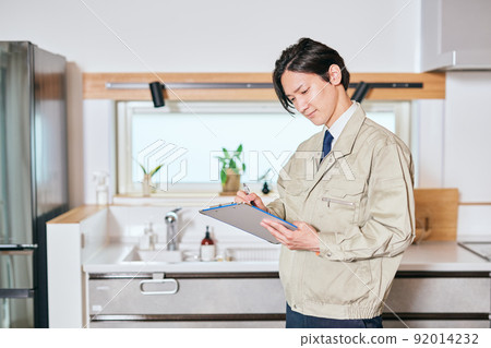A salesman in work clothes taking notes in front of the kitchen 92014232