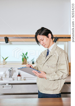 一位身著工作服的推銷員在廚房前做筆記 92014233