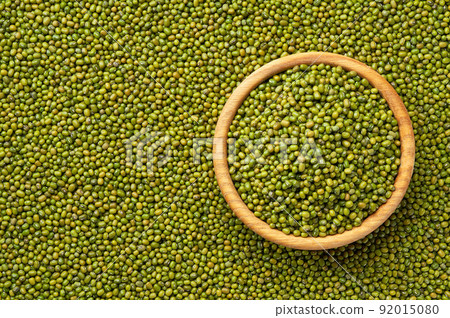 wooden plate with raw mung beans on a mung beans background close-up top view. wooden plate with raw mung beans on a mung beans background close-up top view. 92015080